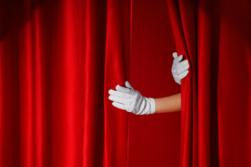 Female hands in white gloves opening red curtains on color background