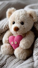 Adorable plush bear holds pink heart, nestled in cozy knit blanket