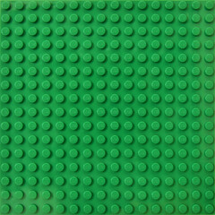 Fototapeta premium Lego green baseplate with rows of round knots to assembly plastic bricks from popular toy brand. Editorial illustrative image of popular children plastic toy.