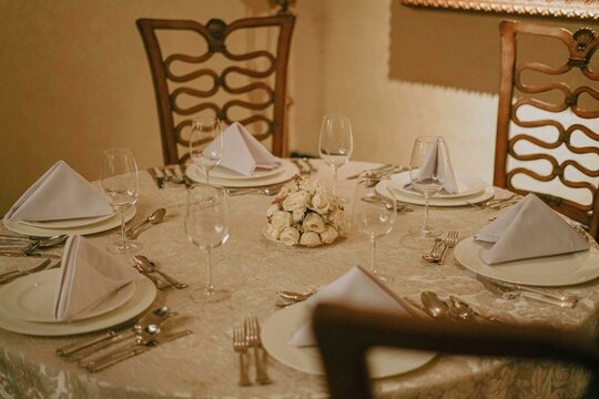 Elegant Dinner Table Setting with White Roses.  A beautifully set table awaits guests for a special occasion.