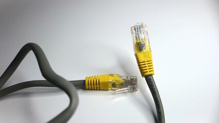 Close-up of two yellow RJ45 connectors on a grey ethernet cable against a white background.  Ideal...