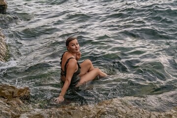 Fototapeta premium Woman Water Rocks - Smiling Woman Sits on Rocks in Sea Water