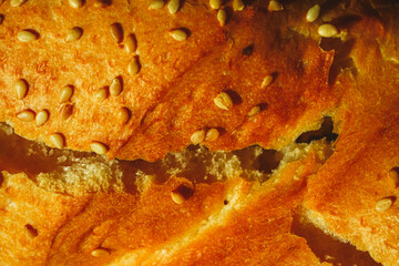 Close-up of a French baguette with sesame seeds. Background with bread texture. Dried wheat loaf, macro photography. Use for banner, menu