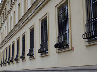 Historic Building Exterior with Decorative Metal Window Guards and Cream Colored Facade in European...