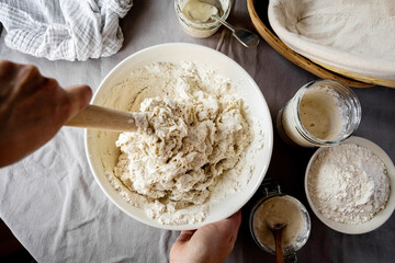 Female hands mixing sourdough dough in a bowl