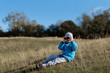 Boy sitting on the grass with binoculars