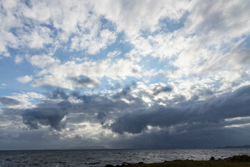 In Scotland, the sunset paints the sky with shades from blue to orange. Clouds dominate the horizon as the sea reflects light and silence in a breathtaking scene.
