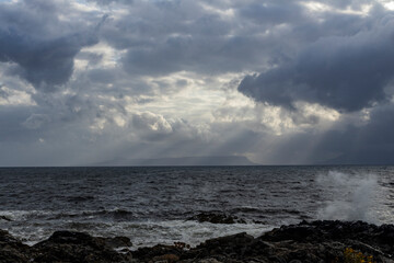 In Scotland, the sunset paints the sky with shades from blue to orange. Clouds dominate the horizon as the sea reflects light and silence in a breathtaking scene.