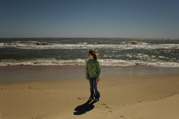 Profile beautiful tween holding cell phone on beach vacation