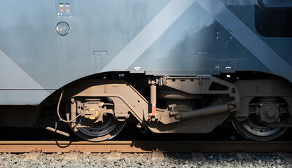 Wheel assembly and undercarriage of a train with wheels on the rail, illuminated by the sun, illuminated by the sun