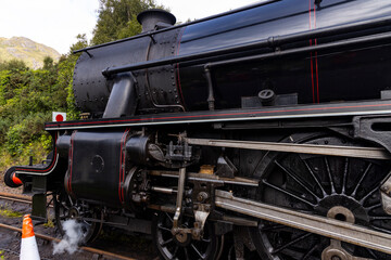 Obraz premium Iconic Jacobite steam train crosses Glenfinnan Viaduct and stops at the station, with historical details, smoke, and nostalgia. Timeless and magical icon in the Scottish Highlands. Locomotive interior