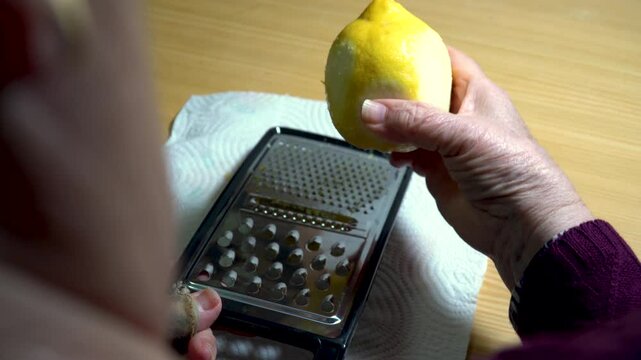 A person zesting the peel of a lemon