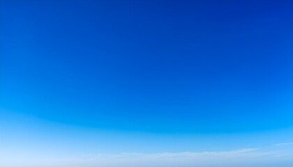 Obraz premium A perfectly clear sky with a stunning gradient of blue, transitioning from a deep azure at the top to a soft pastel blue near the horizon. 
