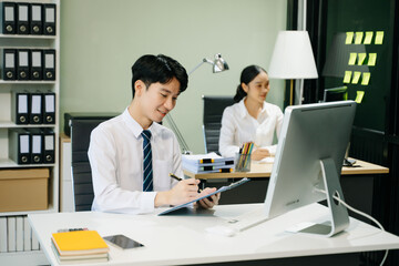 Young businessman working at office with laptop, tablet and taking notes on the paper..