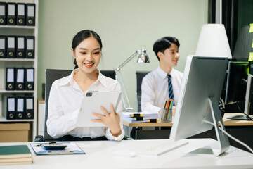 Business woman using tablet and laptop for doing math finance on an office desk, tax