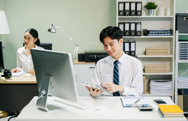 Young businessman working at office with laptop, tablet and taking notes on the paper..