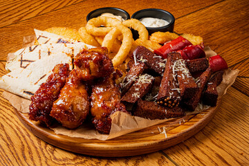 Savor a mouthwatering assortment of crispy chicken wings, rich bites, and onion rings served warm