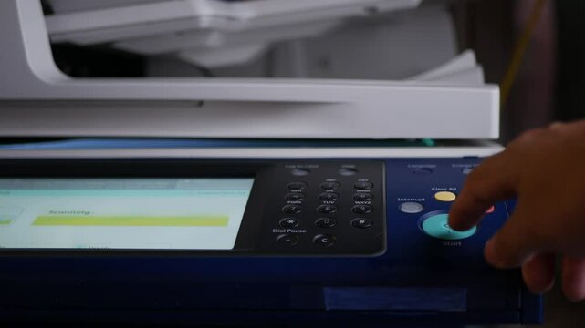 Close up hand office man press start button on panel to using the Office professional multi-function printer scanner for scanning document printing. a Copy machines