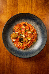 Colorful couscous topped with nuts and flavorful herbs, beautifully presented on a textured plate