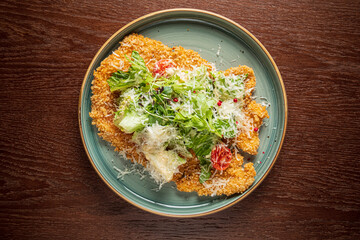 A crispy chicken cutlet with fresh lettuce and savory cheese on a rustic plate
