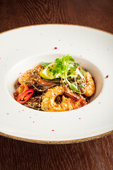 Succulent shrimp nestled on a bed of noodles, adorned with fresh herbs and chilies