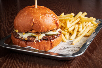 Juicy burger with cheese, pickles, crispy toppings, and golden fries on a tray