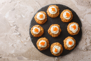 Homemade Carrot oatmeal cookie cake with cream cheese frosting close-up on plate on table. Horizontal top view from above