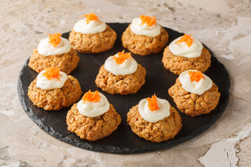 Soft crumbly carrot oatmeal cookie cake with cream cheese frosting close-up on plate on table. Horizontal