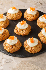 Delicious carrot cake cookies with cream cheese frosting are a must-have Easter dessert close up on the plate on the table. Vertical