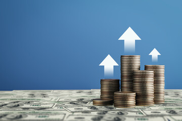 Stacks of coins rising on dollar bills with upward arrows on blue background symbolizing financial...