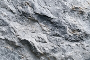 Close-up of rough, grey stone surface with natural cracks and fissures, ideal for background or texture use. 
