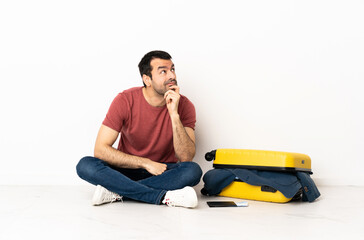 Caucasian handsome man with a suitcase full of clothes sitting on the floor at indoors having...