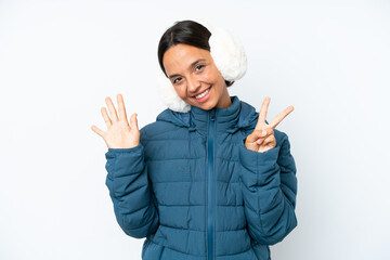 Young hispanic woman wearing a winter earmuffs isolated on white background counting seven with...