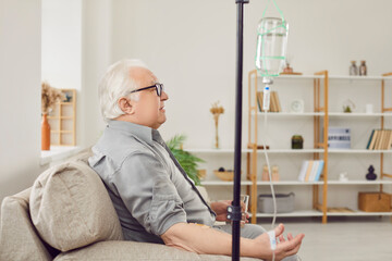 Senior man receiving vitamin therapy while resting on couch at home. Side view, profile portrait of...