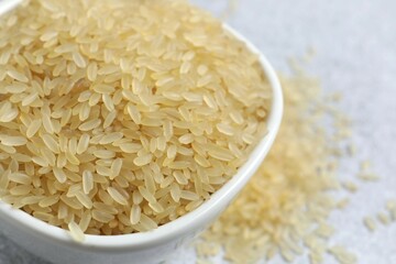 Raw brown rice in bowl on gray background