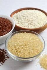 Different types of rice in bowls on table, closeup