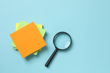Magnifying glass with paper stickers on color background