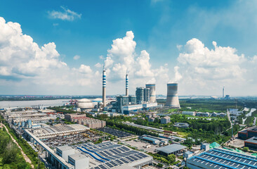 Aerial view of a large power plant complex with cooling towers chimneys solar panels near a river.