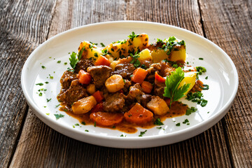 Beef vegetables goulash with potatoes on wooden table