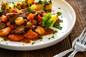 Beef vegetables goulash with potatoes on wooden table