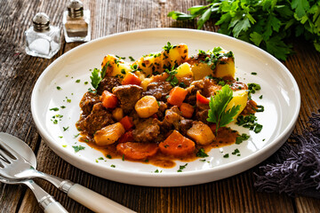 Beef vegetables goulash with potatoes on wooden table