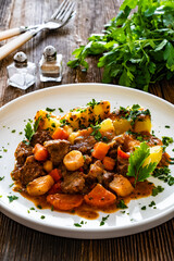 Beef vegetables goulash with potatoes on wooden table