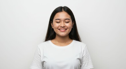 Fototapeta premium Serene Indonesian Woman Smiling with Closed Eyes against a White Backdrop