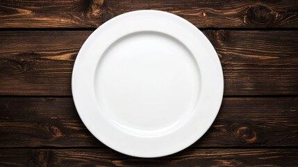 An empty white plate on a wooden table.