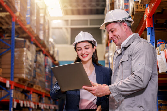 A female manager and a warehouse worker having a discussion in the storage warehouse.