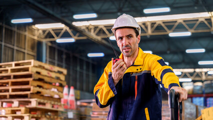 A warehouse worker using a walkie talkie in a storage warehouse.