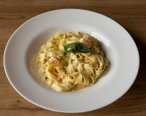 Close up of creamy salmon fettuccine pasta in a white ceramic bowl