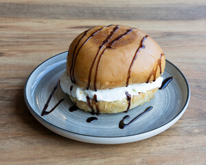 Ice cream burger dessert with chocolate topping served on gray plate for creative sweet visuals