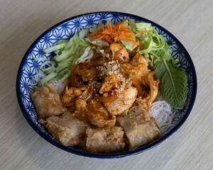 Spicy chicken with vegetables and spring rolls served in bowl for Asian lunch concepts