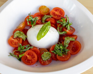 A bowl of caprese salad with tomatoes, mozzarella and basil leaves